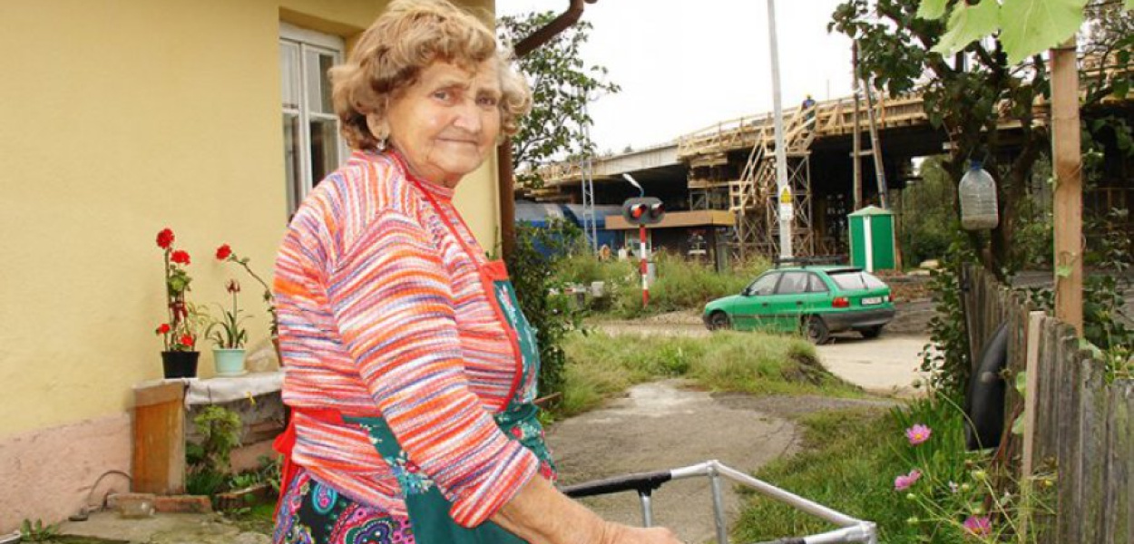 Przejazd kolejowy w Kroczymiechu. Z lewej strony widać fragment domu, w którym mieszka Eugenia Cebulak. W głebi, przy torach, stoi podobna do kiosku budka dróżnika, a nad nią góruje budowany wiadukt drogowy