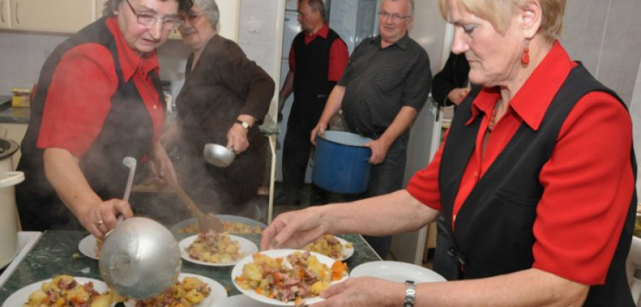 Członkinie stowarzyszenia dziela porcje pieczonych na ogniu ziemniaków