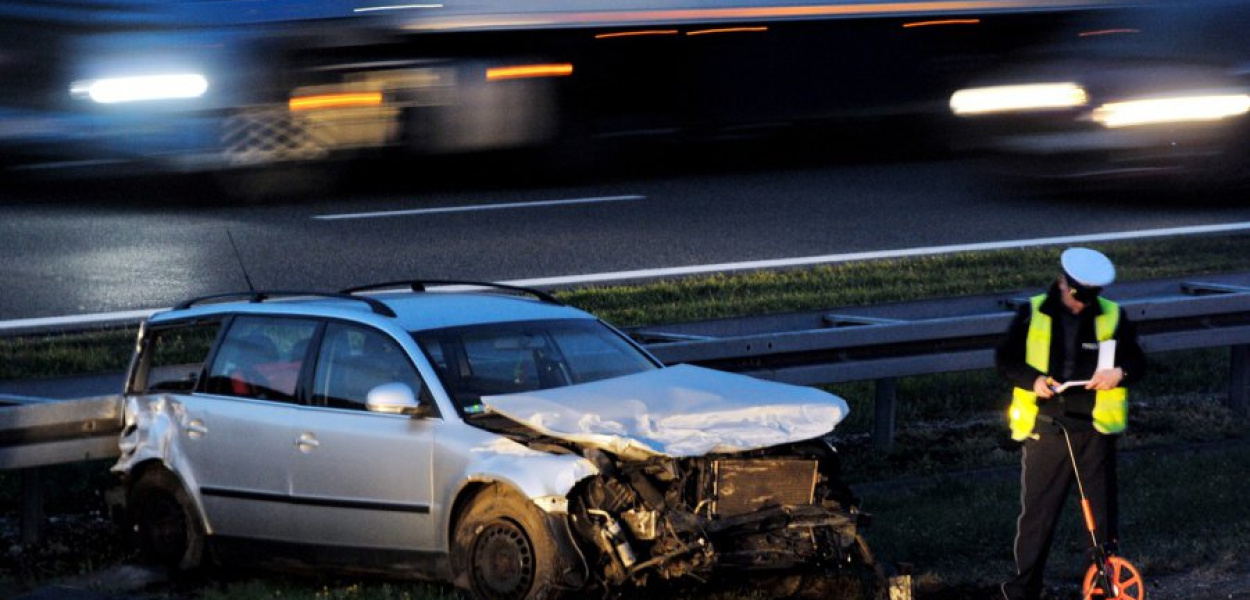Policjanci robią pomiary przy rozbitym volkswagenie passacie
