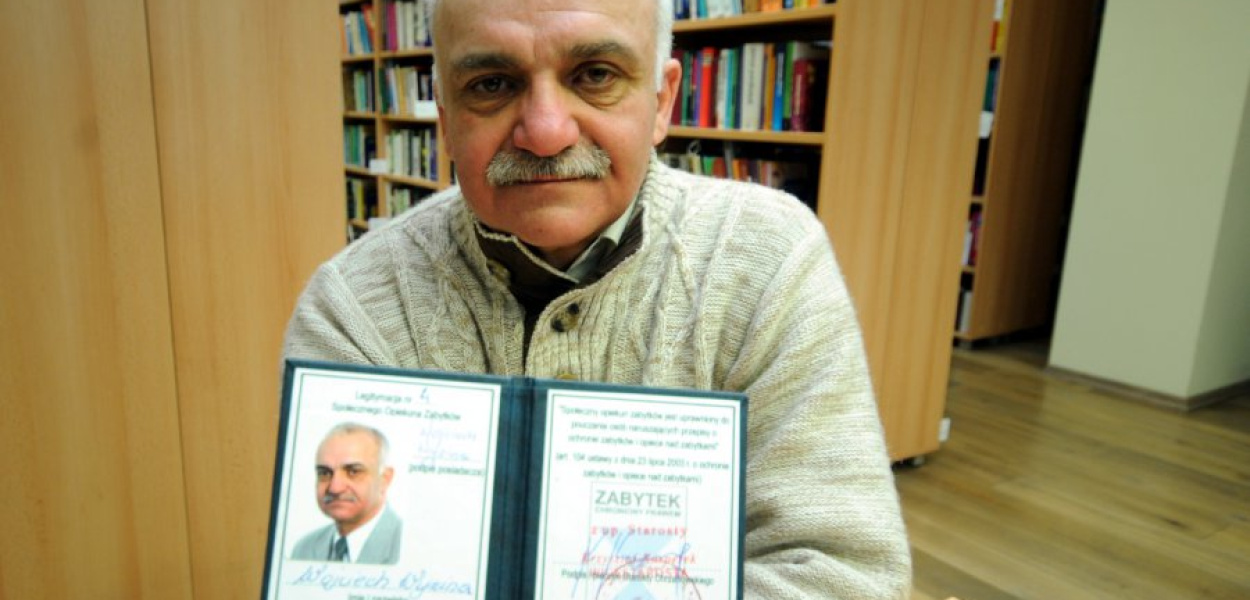 Wojciech Wyzina pokazuje legitymację społecznego opiekuna zabytków