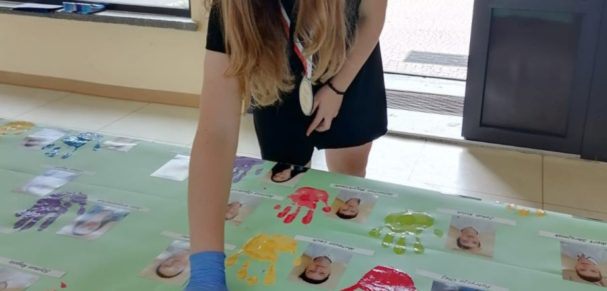 Jedna z uczennic odbija ślad ręki na nietypowym tableau. fot. udostępnione przez szkołę