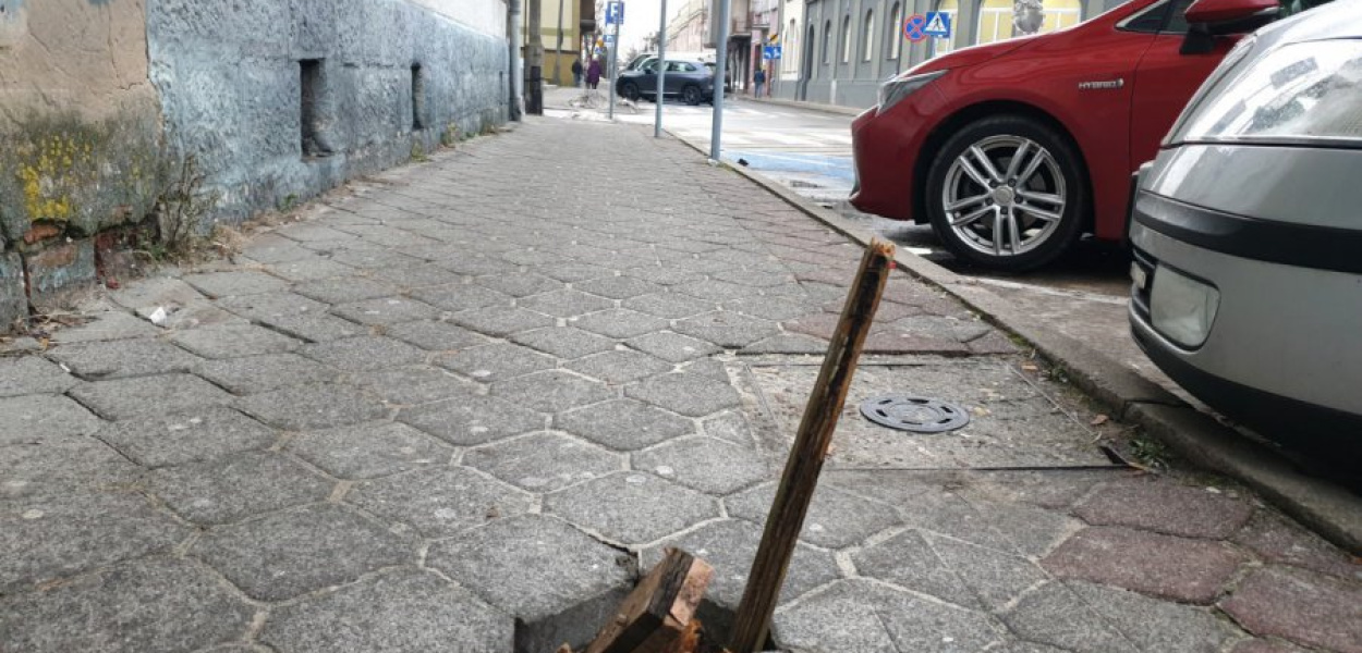 Paliki wetknięte w dziurę w chodniku przy ul. Piłsudskiego w Chrzanowie